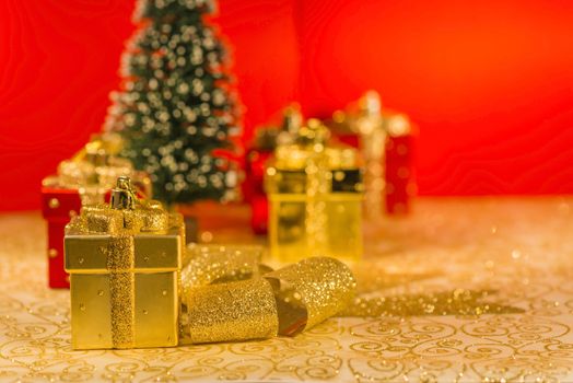 Golden Christmas ornaments, golden ribbon, snowed fir and red Christmas decoration on red background