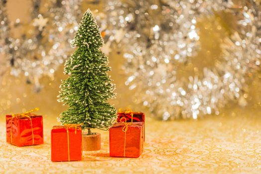 Snowed Christmas tree surrounded by red present boxes