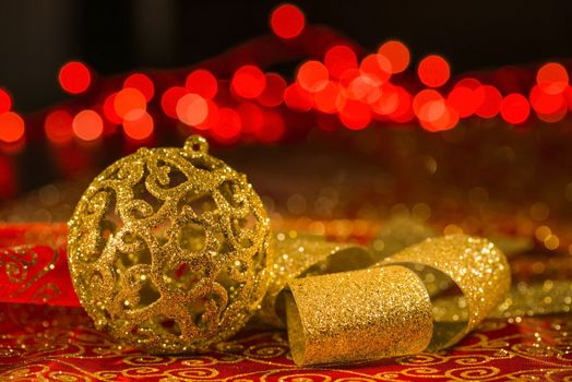 Golden Christmas ornaments and golden shiny ribbon with red lights blur on background