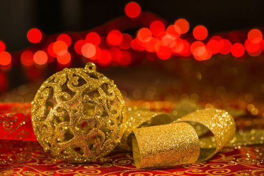 Golden Christmas ornaments and golden shiny ribbon with red lights blur on background