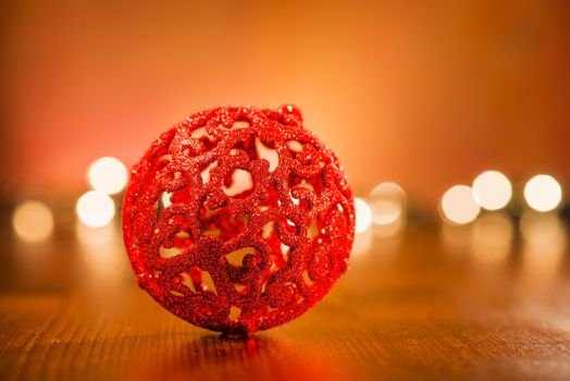 Red Christmas ornament with golden blur lights on wooden base