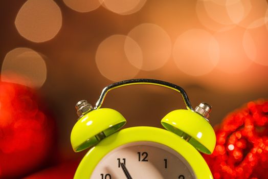 Green alarm clock and Christmas ornaments with light blur background