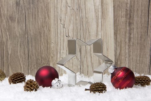 christmas decoration with wooden background, snow, christmas baubles red, poinsettia, and pine cones 