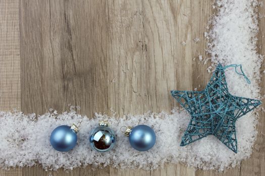 christmas baubles blue and moravian star with wooden background with snow 