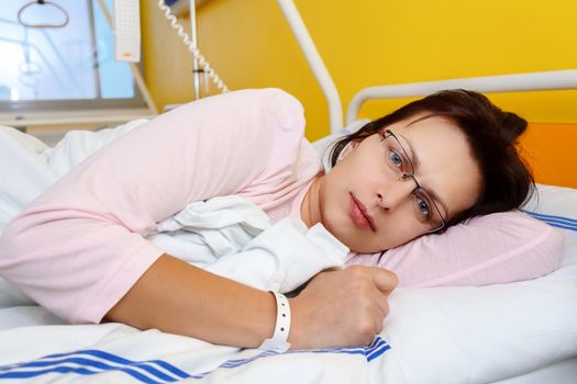 Real people in real situation, sad middle-aged woman lying in hospital with pneumonia