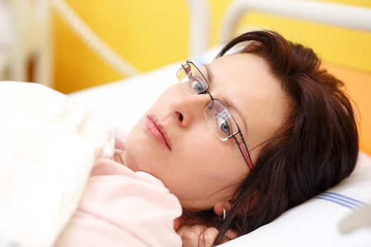 Real people in real situation, sad middle-aged woman lying in hospital with pneumonia