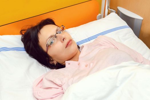 Real people in real situation, sad middle-aged woman lying in hospital with pneumonia