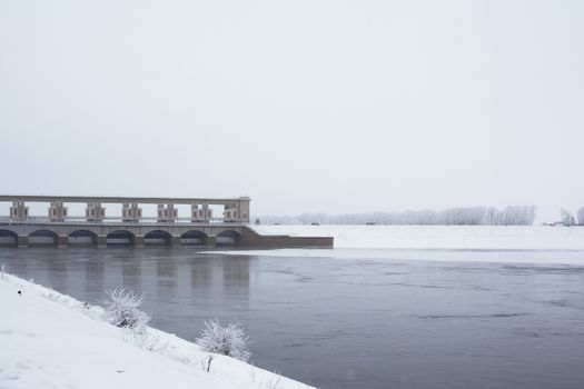 White tree, snow, river and dam in winter
