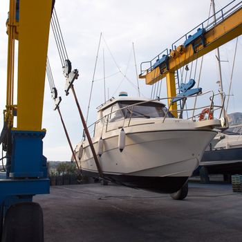 Boat wheel crane elevating motorboat to yearly paint task