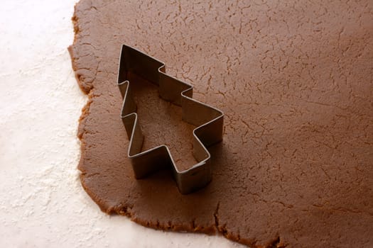 Cutting out a festive Christmas tree shape in gingerbread dough