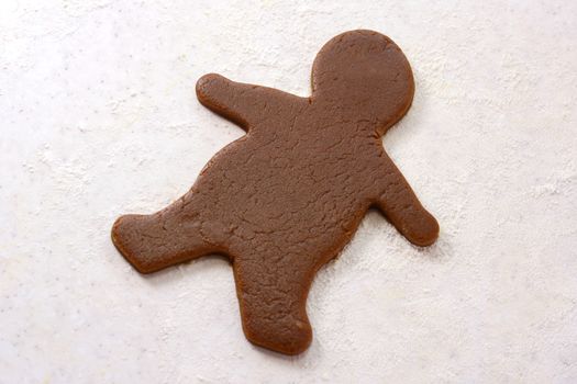 Single uncooked gingerbread man shape in cookie dough