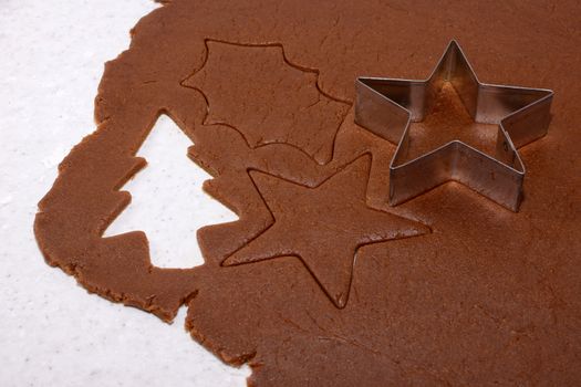 Festive shapes and star cookie cutter on gingerbread cookie dough