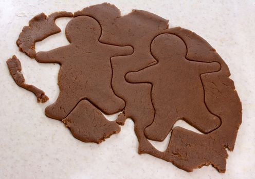 Two gingerbread men shapes cut into cookie dough