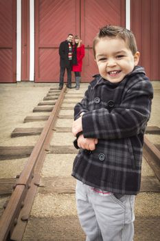 Young Adorable Mixed Race Boy at Train Depot with Parents Smiling Behind.