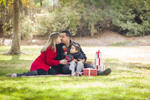 Young Mixed Race Family Enjoying Christmas Gifts in the Park Together.