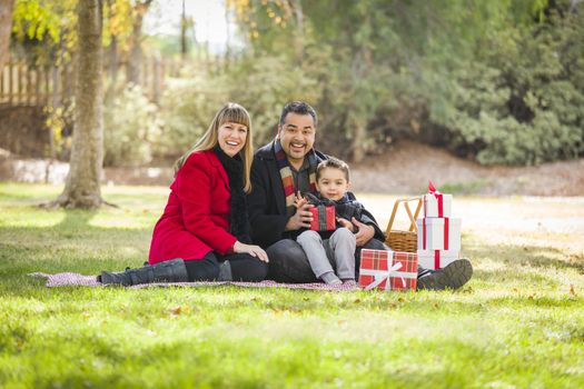 Young Mixed Race Family Enjoying Christmas Gifts in the Park Together.