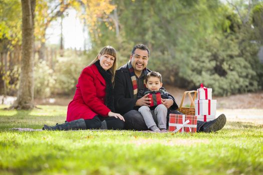 Young Mixed Race Family Enjoying Christmas Gifts in the Park Together.