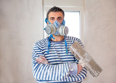construction funny plastering man mason with protective mask and trowel in hands