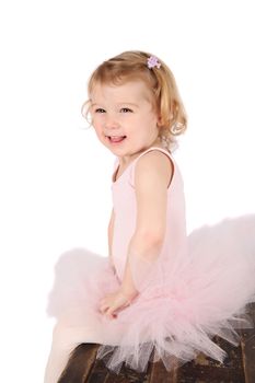 Little ballet girl wearing a pink tutu on an antique trunk
