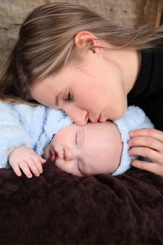 Baby boy sleeping while his mother kisses his cheek