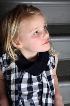 Blond girl sitting on staircase with serious expression
