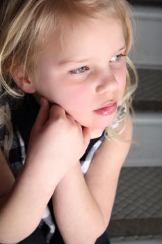 Blond girl sitting on staircase with serious expression