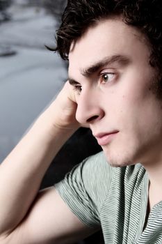 Attractive brunette male sitting by window in thought