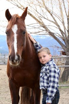 Young boy in blue leaning against his horse