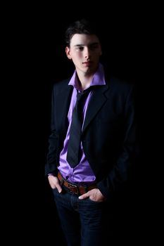 Attractive brunette male model on black background wearing jeans and tie