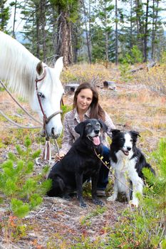 Beautiful brunette cowgirl with her horse and dogs