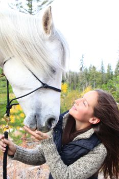 Beautiful young brunette cowgirl with her white horse