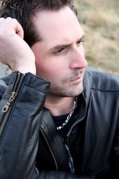 Attractive male outdoors wearing a black leather jacket