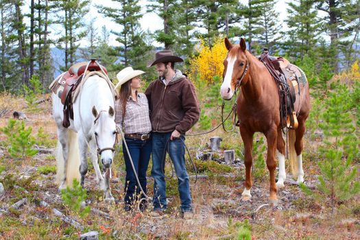 Cowboy and cowgirl in the mountains with their horses