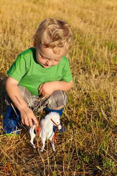 Cute blond toddler playing outside in the hay fields