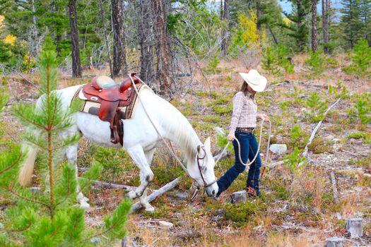 Beautiful brunette cowgirl with her horse on a mountain trail ride 