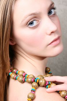 Beautiful blonde girl with colorful beads against grey