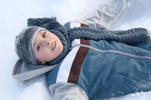 Young boy playing outside in the snow on a cold day