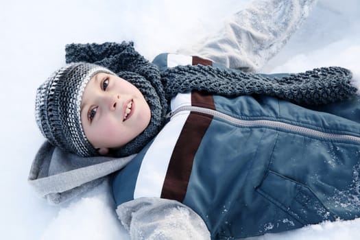 Young boy playing outside in the snow on a cold day