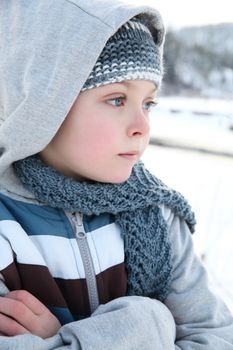 Young boy playing outside in the snow on a cold day
