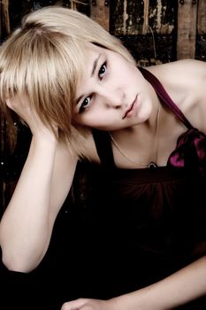 Beautiful blond female with serious expression against wooden background