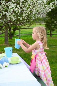 Little blond girl playing outside in garden with spring blossoms