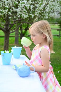 Little blond girl playing outside in garden with spring blossoms