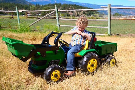 Young boy with curly blond hair playing in the hay field