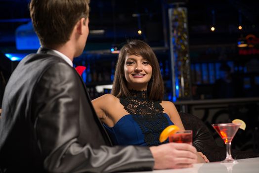 portrait of a woman in a nightclub, sitting on the couch and talking with man