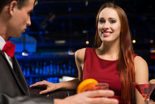 portrait of a woman in a nightclub, sitting on the couch and talking with man