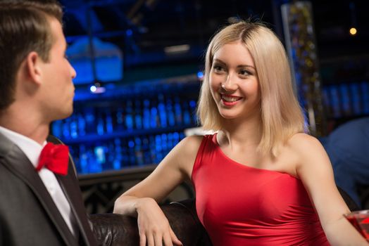 portrait of a woman in a nightclub, sitting on the couch and talking with man