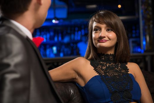 portrait of a woman in a nightclub, sitting on the couch and talking with man