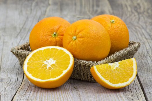 fresh oranges in a basket on old wooden background