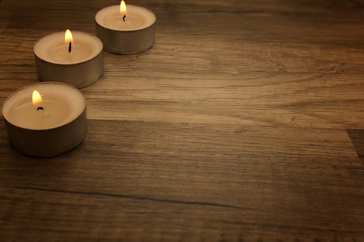 several tea lights with wooden background