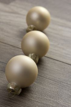 several christmas baubles creme on wooden background as christmas decoration 